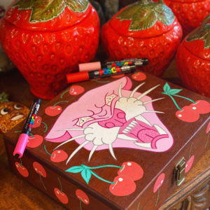 Photo of a hand painted wooden box with a pink panther and red cherries