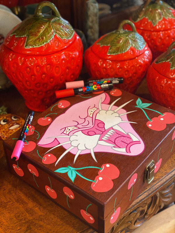 Photo of a hand painted wooden box with a pink panther and red cherries